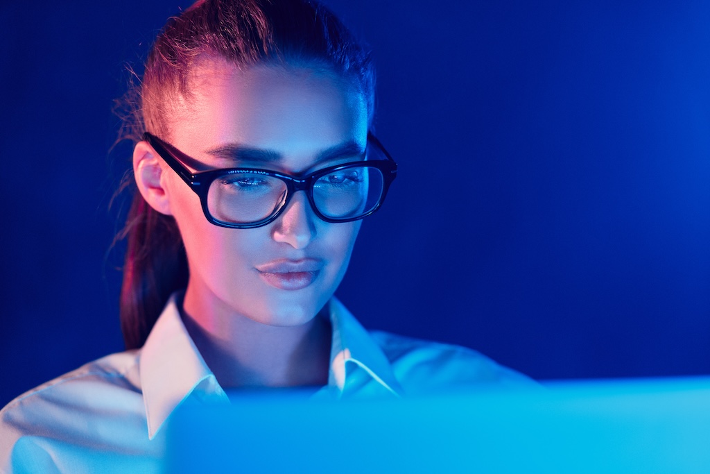 Night Online Work. Woman using laptop in colorful neon lights Night Online Work. Woman using laptop in colorful neon lights